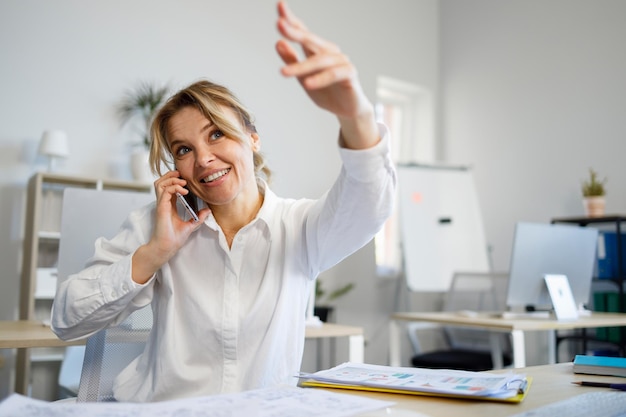 Biznesowa kobieta rozmawiająca przez telefon komórkowy prosi o czekanie