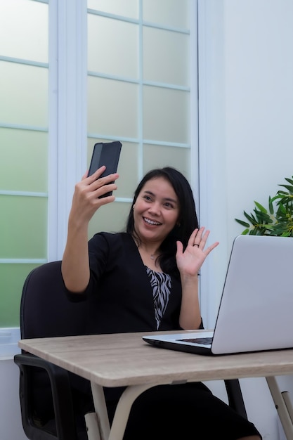 Biznesowa Kobieta Siedzi Na Krześle I Macha Do Telefonu Komórkowego Przed Laptopem