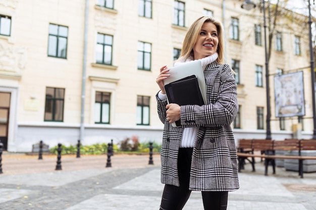 Biznesowa kobieta śpiesząca się do biura z laptopem w dłoniach