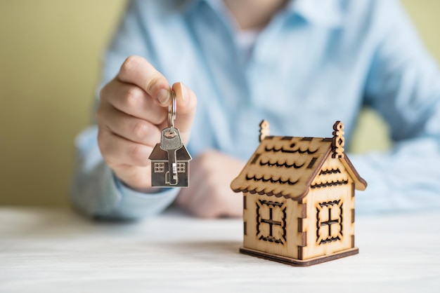 Biznesowa kobieta trzyma klucz z breloczkiem w kształcie domu Koncepcja kredytu hipotecznego Przeprowadzka lub wynajem nieruchomości
