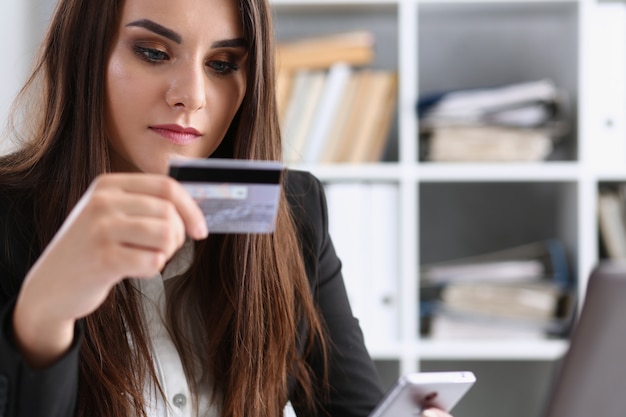 Biznesowa kobieta w biurze trzyma w ręce plastikową kredytową kartę debetową