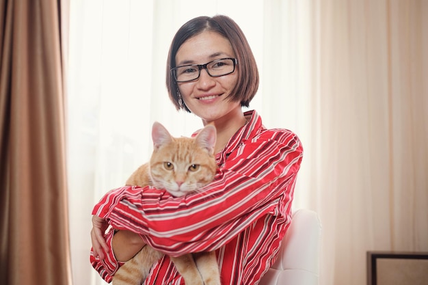 Biznesowa kobieta w czerwonej koszuli z rudym kotem w domu