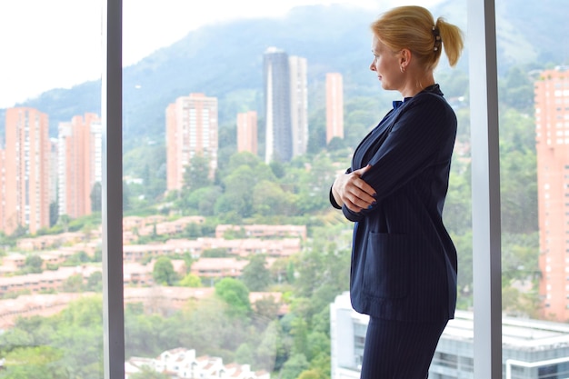 biznesowa kobieta w garniturze przy panoramicznym oknie w biurze dziewczyna w biznesowej kurtce w pracy