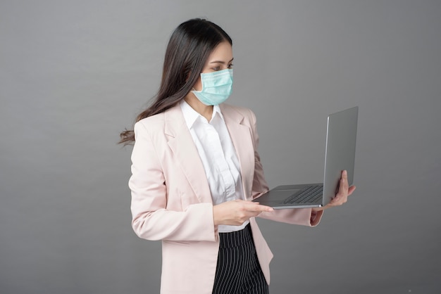 Biznesowa kobieta z chirurgicznie maską trzyma laptop