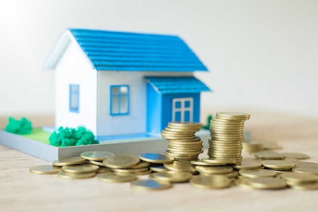 Zdjęcie biznesowa koncepcja nieruchomości model domu ze stosem monet na drewnianym stole i bokeh w tle