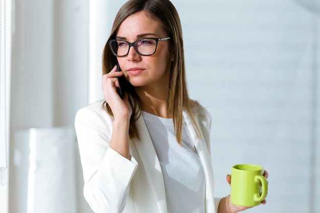 Biznesowa Młoda Kobieta Używa Jej Telefon Komórkowego W Biurze.