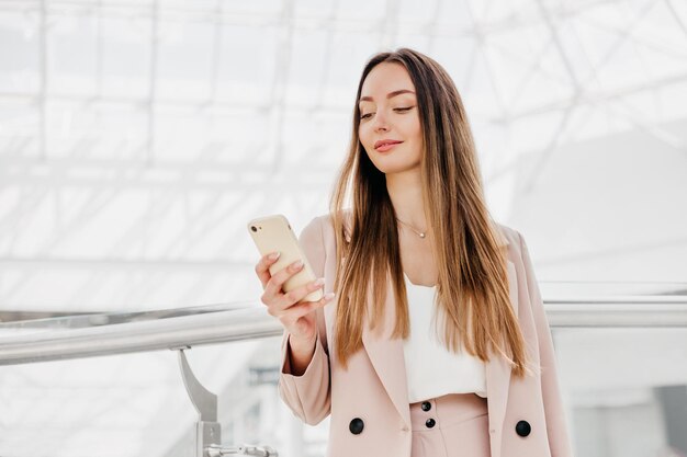 Biznesowa Młoda Kobieta W Garniturze Używa Swojego Telefonu Komórkowego I Patrzy Na Ekran