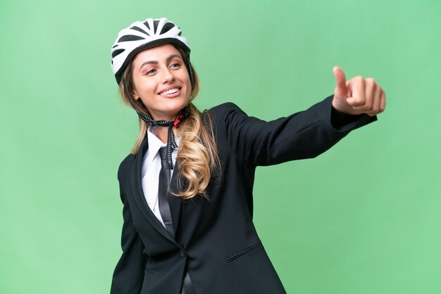 Biznesowa Urugwajska kobieta ubrana w kask motocyklisty na odosobnionym tle, dająca kciuk do góry gestowi