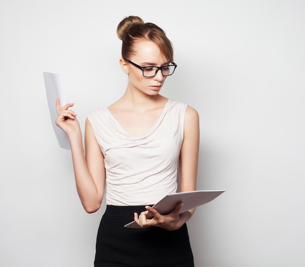 Biznesowe finanse i ludzie koncepcja młoda biznesowa kobieta trzyma strony papieru Pracownik biurowy na szarym tle