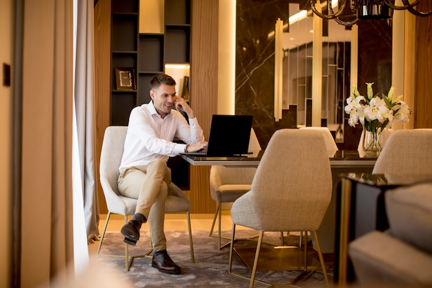 Biznesowego mężczyzna obsiadanie w luksusowym pokoju przed laptopem