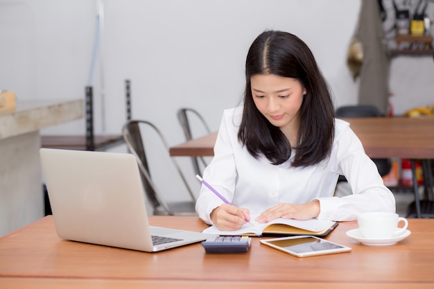 Biznesowy azjatykci kobiety writing na notatniku na stole z laptopem