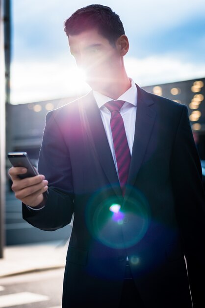 Biznesowy mężczyzna texting na wieczór outdoors