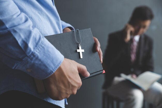 Biznesowy mężczyzna trzyma biblię w miejscu pracy.