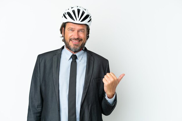Biznesowy starszy mężczyzna z kaskiem rowerowym na białym tle wskazujący na bok, aby zaprezentować produkt