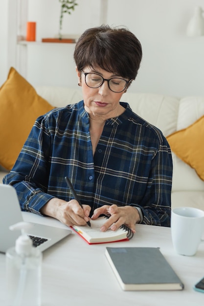 Bizneswoman lub bloger pracujący na laptopie siedzący w domu i zarządzający swoim biznesem przez ho