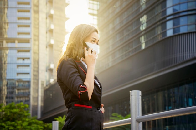 Zdjęcie bizneswoman nosi maskę podczas rozmowy telefonicznej