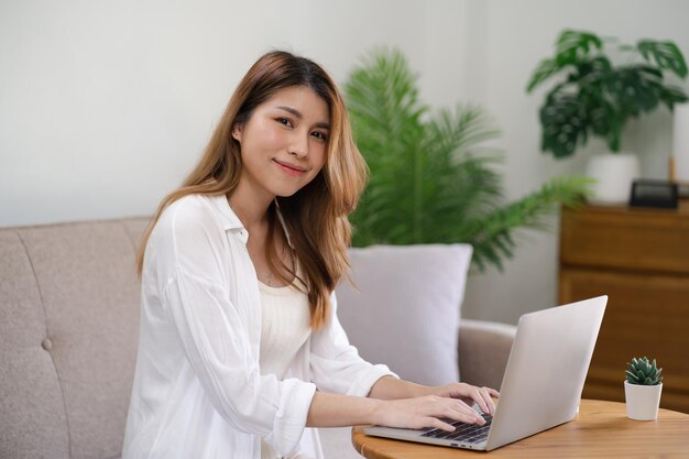 Bizneswoman pracująca w domu pracuje online na laptopie Azjatycka bizneswoman pracująca na kanapie biznes online z laptopem z dystansem społecznym spotkanie online