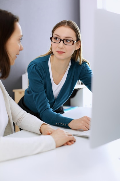 Bizneswoman przedstawia prezentację swojej koleżance, gdy siedzą przy biurku