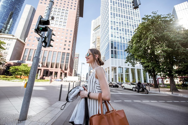 Bizneswoman ubrana swobodnie, przechodząc przez ulicę w nowoczesnej dzielnicy Frankfurtu