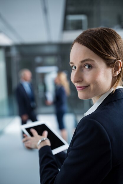 Bizneswoman używa cyfrową pastylkę w biurowym korytarzu