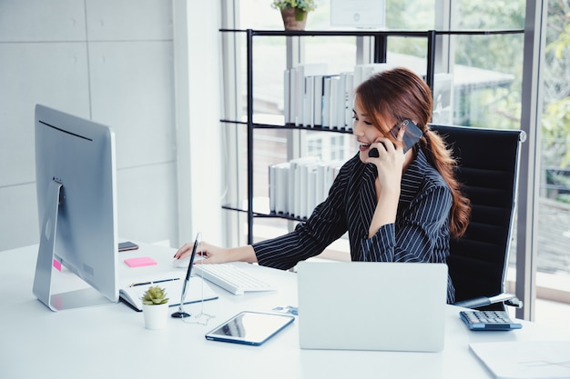 Bizneswoman używa telefon komórkowego podczas gdy pracujący w jej biurze.