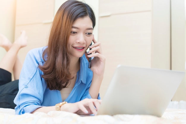 Bizneswoman używa wiszącą ozdobę i laptop na łóżku.