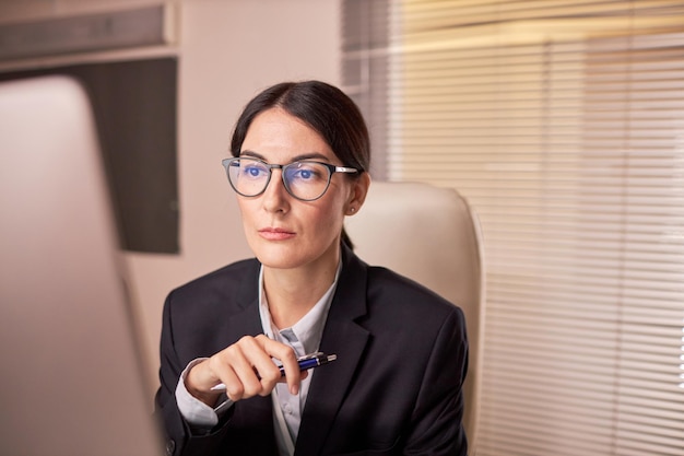 Bizneswoman w okularach i patrząc na ekran komputera