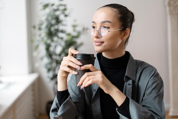 Bizneswoman w okularach to młoda kobieta pijąca kawę pomiędzy pracą