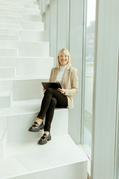 Bizneswoman z cyfrowym tabletem na nowoczesnych schodach biurowych