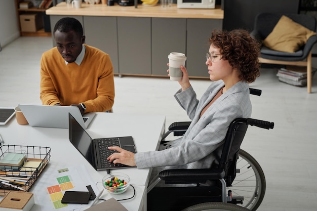 Bizneswoman z niepełnosprawnością pracuje na laptopie w biurze