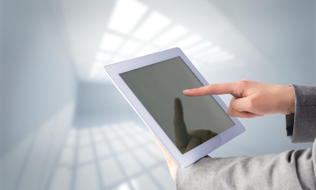 Bizneswoman za pomocą komputera typu tablet przeciwko pokoju z oknami na suficie