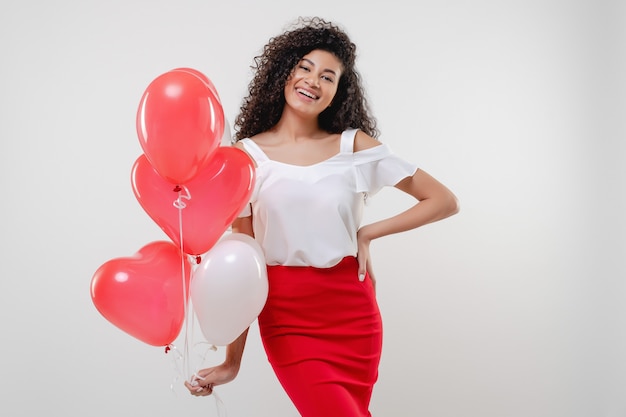 Bkack kobieta z kolorowymi czerwonymi serce kształtującymi balonami odizolowywającymi