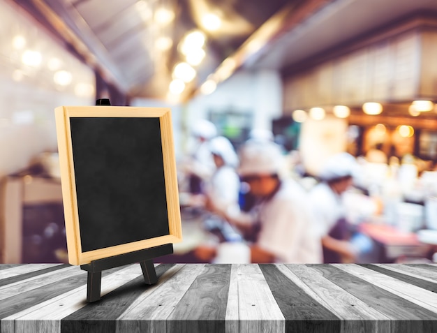 Blackboard menu z sztalugą na drewnianym stole z plamy otwartą kuchnią