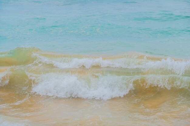 Błękitne fale oceanu i żółty piasek plaży.