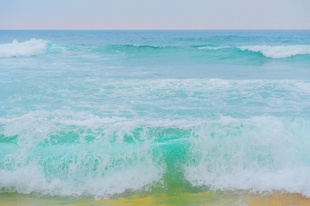 Błękitne fale oceanu i żółty piasek plaży.