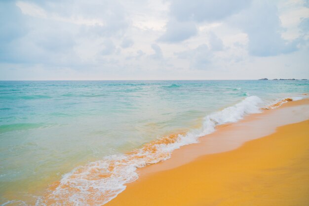 Błękitne fale oceanu i żółty piasek plaży.