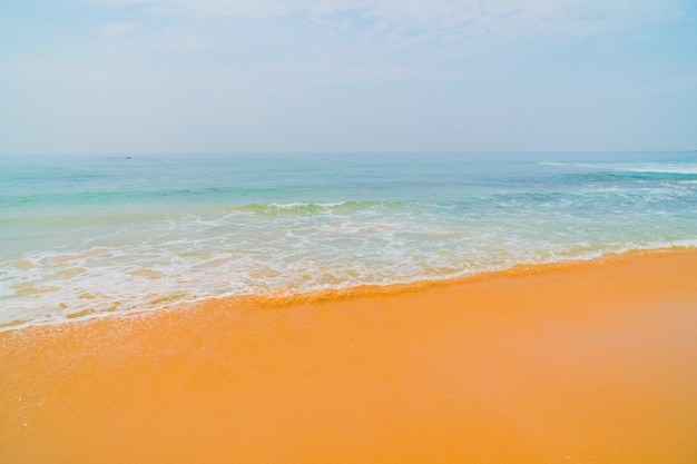 Błękitne fale oceanu i żółty piasek plaży.