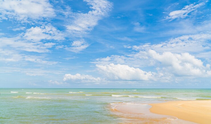 Błękitne niebo biała chmura nad piaszczystą plażą z białą pienistą