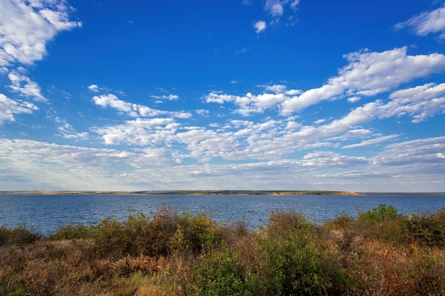 Błękitne niebo nad brzegiem rzeki jesienią z białymi chmurami miękkie wieczorne światło