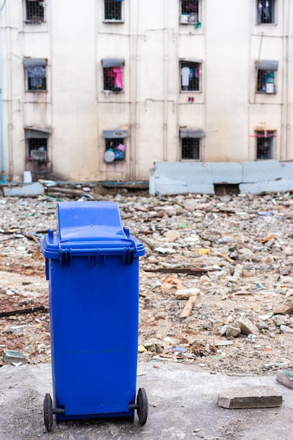 Błękitny kosz na śmieci z starym budynkiem