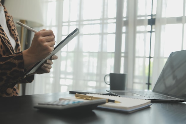 Bliska Biznes kobieta za pomocą kalkulatora i laptopa do matematyki finansów na drewnianym biurku statystyki rachunkowości podatkowej i koncepcji badań analitycznych