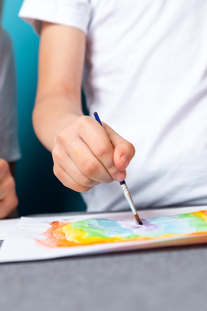Zdjęcie bliska chłopca malować akwarelę pracę domową do przedszkola na niebieskiej powierzchni