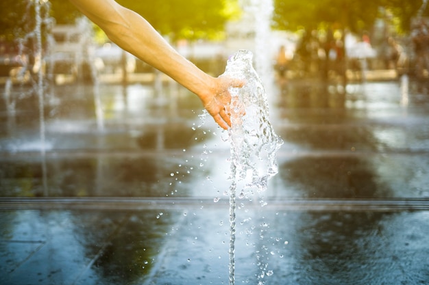 bliska dłoni osoby dotknąć fontanny wody na ulicy latem na zewnątrz