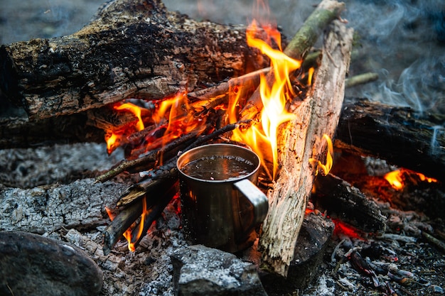 Bliska herbaty w metalowym kubku ogrzewa się w ognisku