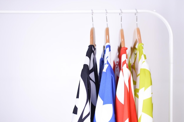 Bliska kolekcja ubrań wiszących na drewnianym wieszaku na ubrania w szafie lub odzieży.