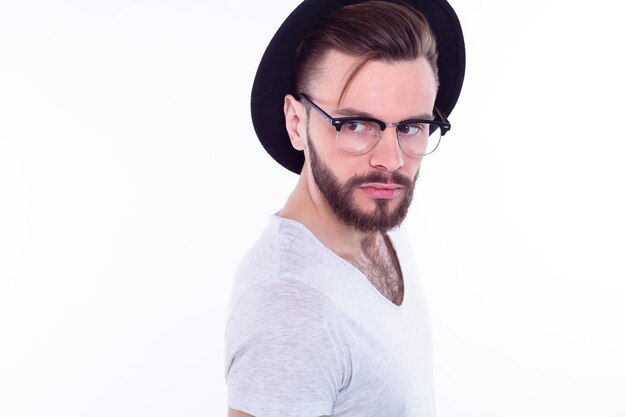 Bliska moda portret młodego brodatego mężczyzny Uśmiechnięty hipster facet Przystojny mężczyzna w stylowym kapeluszu Brutalny brodaty chłopak w modnych okularach