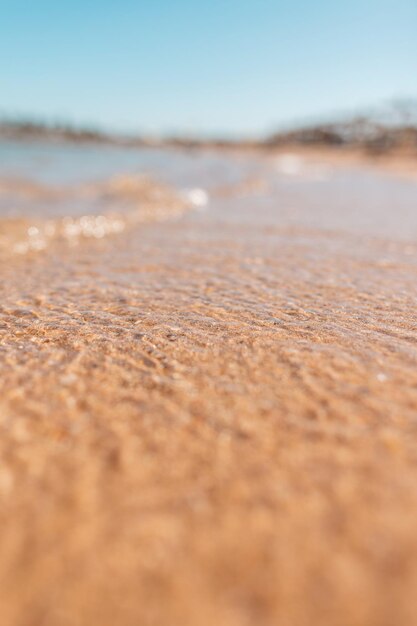 Bliska natura woda na plaży w pobliżu morza. Piękny krajobraz z błękitnym niebem i czystą wodą z żółtym piaskiem na plaży