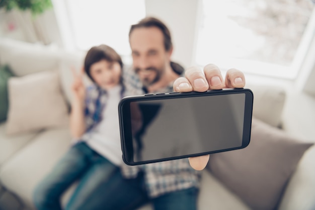 Bliska Portret Fotograficzny Pozytywnie Zrelaksowany Miły Zadowolony Tata Robi Selfie Ze Swoim Młodszym Synem Na Telefonie Siedzi Na Wygodnej Kanapie Odpoczywając Wolny Czas W Weekend W Salonie