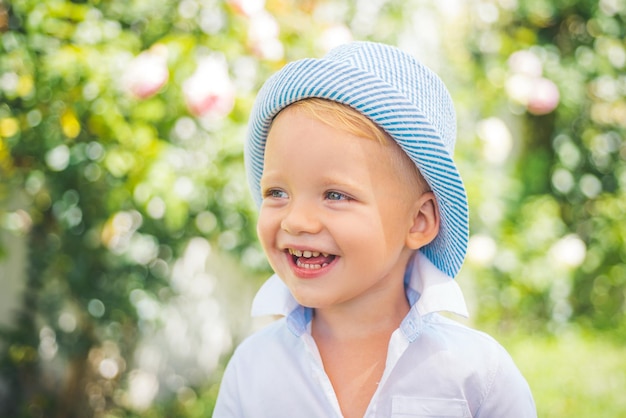Bliska portret ładny chłopiec uśmiechający się na zewnątrz Zbliżenie headshot portret uruchomienia małego chłopca na tle przyrody szczęśliwy mały przedszkolak dziecko Szczęśliwe dzieci emocje uśmiechnięta twarz