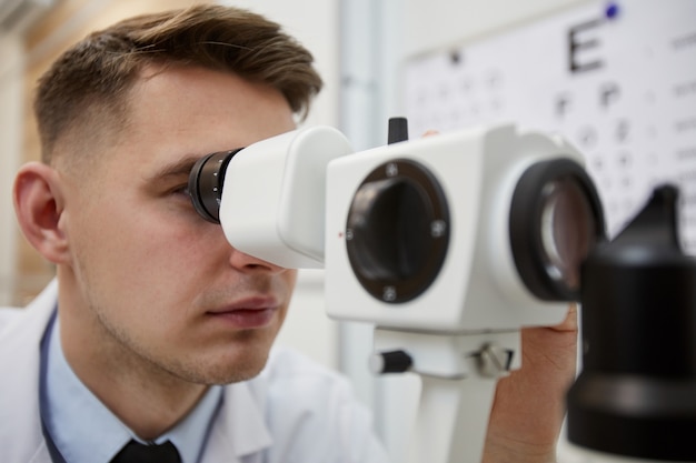 Bliska portret mężczyzny optometrysta za pomocą refraktometru